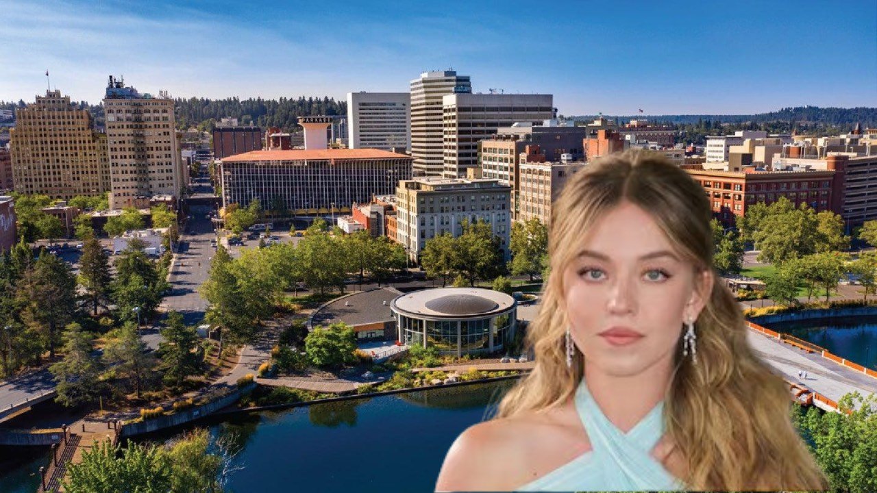 Sydney Sweeney poses in front of a vibrant cityscape, highlighting the dynamic atmosphere of urban living.
