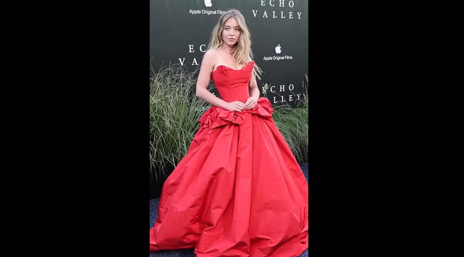 Sweeney in a striking red gown attends the premiere event for a new Disney film, showcasing elegance and excitement.