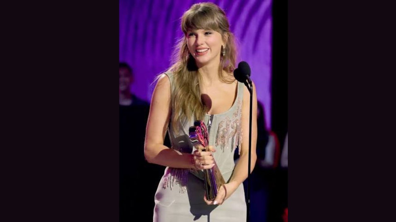Taylor Swift receiving the Best Female Video award at American Music Awards, smiling and holding her trophy.