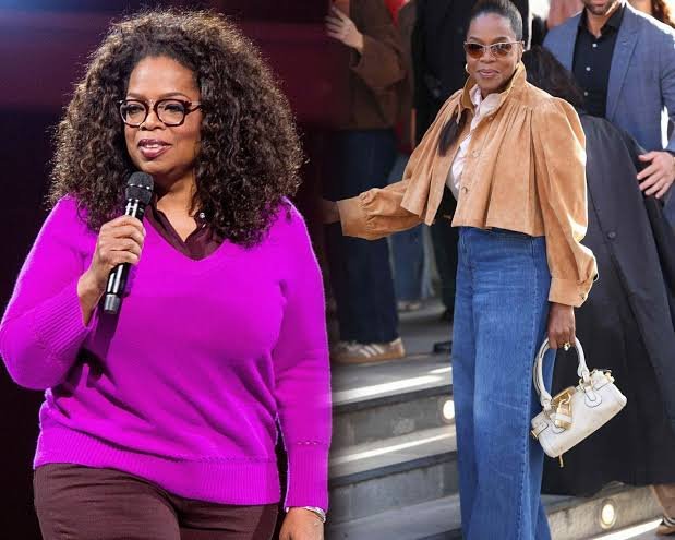 Oprah is wearing a pink sweater smiling warmly at the camera.